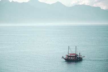 Yolcularla dolu bir tekne. Tekne gezileri ve gezi konsepti. Arkaplanda dağlar.