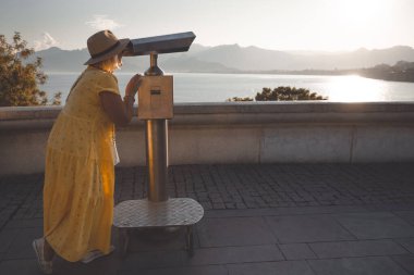 Olgun kadın gezgin dağlarda ve denizde turist dürbününden bakıyor. Emekli insanlar için seyahat kavramı.