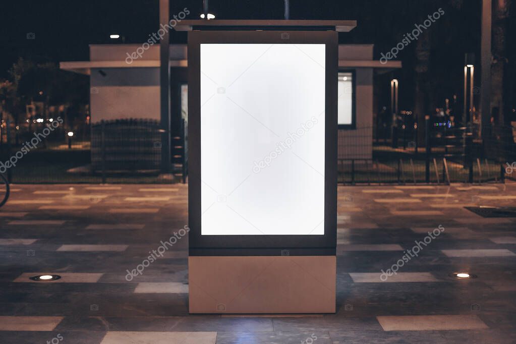 Street advertising mock up template with copy space. Outdoor commercial banner with white empty display on the night street.