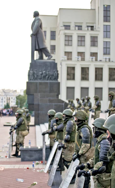 Belaruslu polisler, Lenin anıtının arka planında protesto çiçekleriyle kalkanların önünde dikiliyorlar. Beyaz Rusya cumhurbaşkanlığı seçimlerinden sonra Beyaz Rusya 'da barışçıl protesto