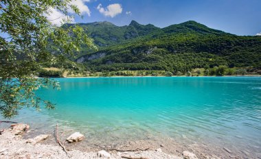 Tenno Gölü 'nün güneşli manzarası İtalyan dağlarıyla çevrili.