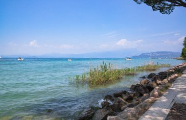 Tembel plajlar, Garda Gölü, İtalya, mavi karınca turkuvaz suyu, sazlık ve tekneler.