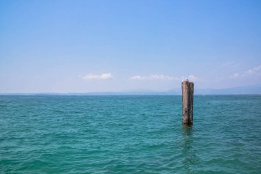 Ufkun önündeki direkte oturan kuşlar Garda İtalya Gölü 'nde.