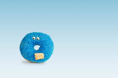 Mavi donutlu, gözleri ve bisküvisi mavi arka planda, yumuşak gölgeli.