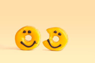 Çikolata gülüşlü iki taze sarı donut kayıp ısırık sarı arka planda izole edilmiş yumuşak gölgeli