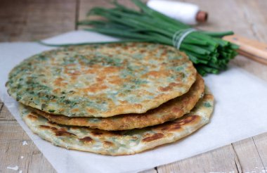 Ev yapımı iştah açıcı yeşil soğan krep ve bir demet yeşil soğan. Rustik tarzı, seçici odak.