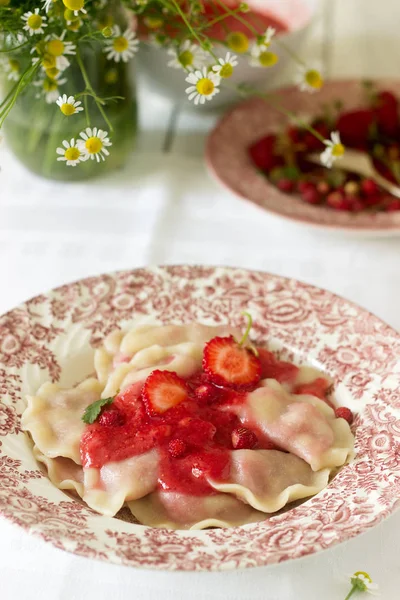 A hearty homemade breakfast or lunch - dumpling or vareniki with strawberries and strawberry sauce. Rustic style, selective focus.