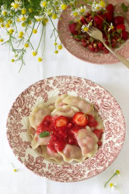 Bir ev yapımı kahvaltı veya öğle yemeği - hamur tatlısı veya çilek ve çilek sosu ile vareniki. Rustik tarzı, seçici odak.