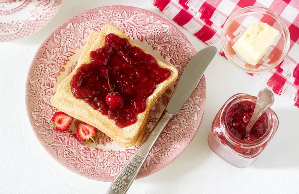 Petit déjeuner de pain grillé au beurre et confiture fraise-rhubarbe, servi avec thé. Style rustique . — Photo