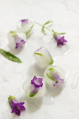 Çiçek ve otlar ışık mermer zemin ile parlak buz küpleri.