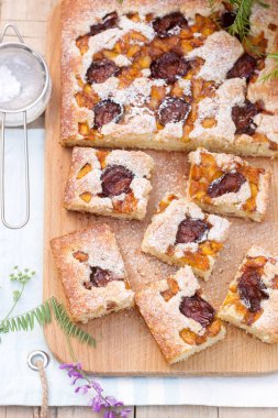 Meyve pasta adet Erik ve şeftali ve ahşap bir masaya çiçek bir buket ile parçaları. Rustik tarzı, seçici odak.