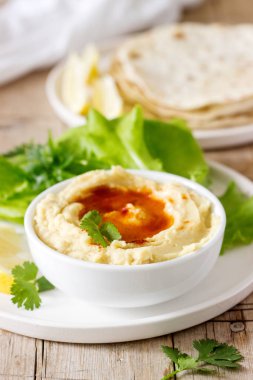 Humus ile zeytinyağı ve kırmızı biber, pide, limon ve ile servis edilir marul yaprakları. Seçici odak.