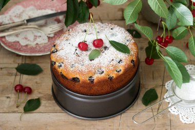 Kirazlı turta, kiraz dallar bir arka plan üzerinde ahşap bir masa üzerine pudra şekeri serpilir. Rustik tarzı, seçici odak.