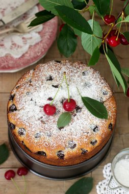 Kirazlı turta, kiraz dallar bir arka plan üzerinde ahşap bir masa üzerine pudra şekeri serpilir. Rustik tarzı, seçici odak.