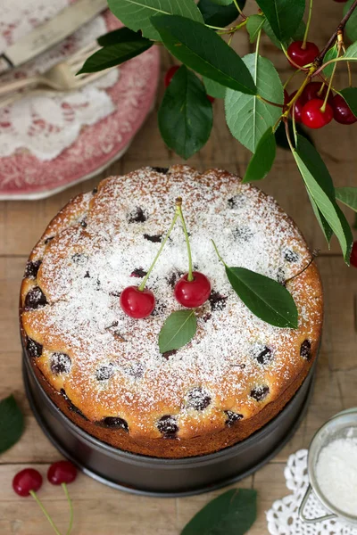 Kirazlı turta, kiraz dallar bir arka plan üzerinde ahşap bir masa üzerine pudra şekeri serpilir. Rustik tarzı, seçici odak.