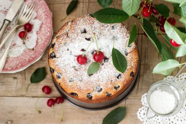 Kirazlı turta, kiraz dallar bir arka plan üzerinde ahşap bir masa üzerine pudra şekeri serpilir. Rustik tarzı, seçici odak.