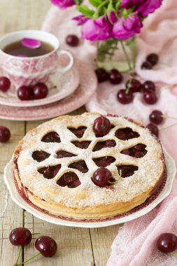 Kirazlı turta kalp şeklinde süsleme çay, bir buket çiçek ve olgun kiraz meyveleri ile bir fincan ile dekore edilmiştir. Vintage tarzı, seçici odak.