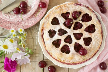 Kirazlı turta kalp şeklinde süsleme çay, bir buket çiçek ve olgun kiraz meyveleri ile bir fincan ile dekore edilmiştir. Vintage tarzı, seçici odak.