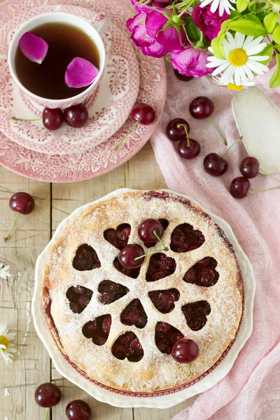 Kirazlı turta kalp şeklinde süsleme çay, bir buket çiçek ve olgun kiraz meyveleri ile bir fincan ile dekore edilmiştir. Vintage tarzı, seçici odak.