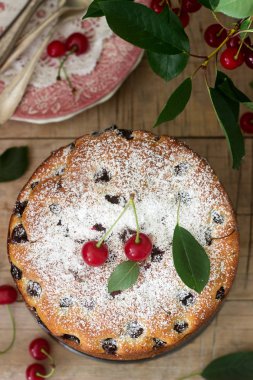 Kirazlı turta, kiraz dallar bir arka plan üzerinde ahşap bir masa üzerine pudra şekeri serpilir. Rustik tarzı, seçici odak.