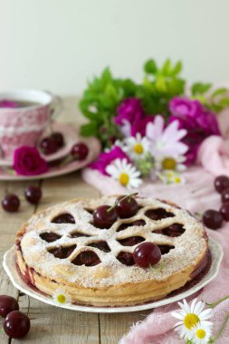 Kirazlı turta kalp şeklinde süsleme çay, bir buket çiçek ve olgun kiraz meyveleri ile bir fincan ile dekore edilmiştir. Vintage tarzı, seçici odak.