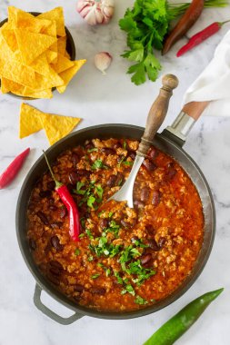 Mexican and American food Chili con carne served with nachos, pepper and herbs. Selective focus. clipart
