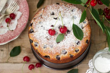 Kirazlı turta, kiraz dallar bir arka plan üzerinde ahşap bir masa üzerine pudra şekeri serpilir. Rustik tarzı, seçici odak.