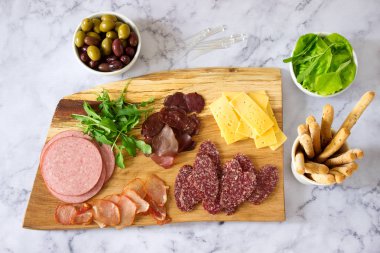 Meze tablo için şarap ya da bira ile sosis, kurutulmuş et ve peynir, grisini, otlar ve zeytin ile servis. Seçici odak.