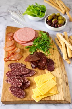 Meze tablo için şarap ya da bira ile sosis, kurutulmuş et ve peynir, grisini, otlar ve zeytin ile servis. Seçici odak.