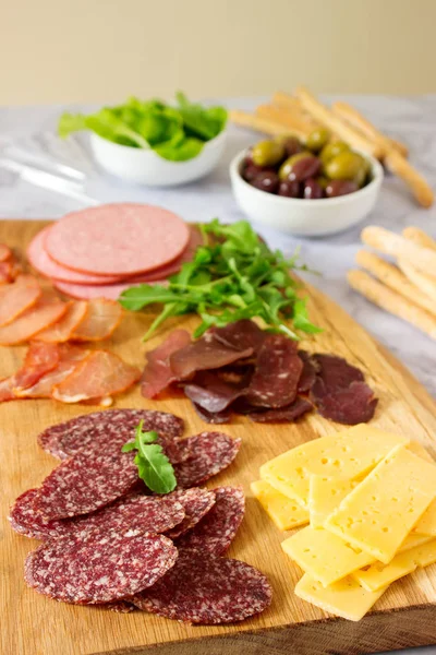 Meze tablo için şarap ya da bira ile sosis, kurutulmuş et ve peynir, grisini, otlar ve zeytin ile servis. Seçici odak.