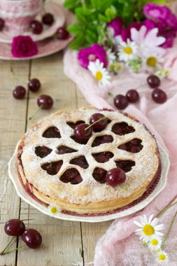 Kirazlı turta kalp şeklinde süsleme çay, bir buket çiçek ve olgun kiraz meyveleri ile bir fincan ile dekore edilmiştir. Vintage tarzı, seçici odak.