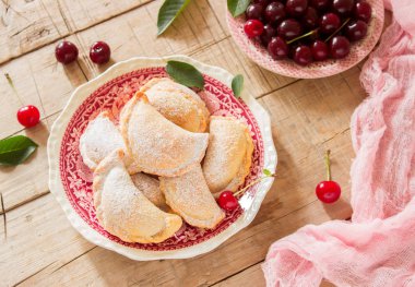 Turta ile kiraz, pudra şekeri ve meyveleri taze Kiraz ahşap yüzeye serpilir. Seçici odak.