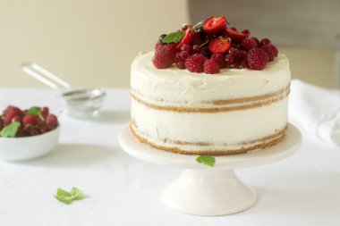 Yaz ev bisküvi kek lor kremalı taze çilek, çilek, ahududu ve kuş üzümü ile dekore edilmiştir. Seçici odak.