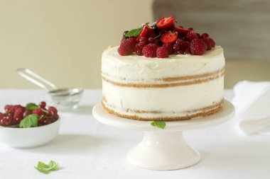 Yaz ev bisküvi kek lor kremalı taze çilek, çilek, ahududu ve kuş üzümü ile dekore edilmiştir. Seçici odak.