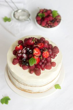 Yaz ev bisküvi kek lor kremalı taze çilek, çilek, ahududu ve kuş üzümü ile dekore edilmiş.