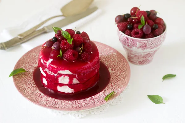 Ice cream cake with berry topping, fresh berries and mint on a light background. Selective focus.