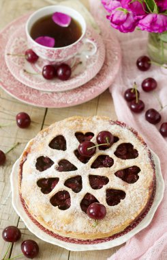 Kirazlı turta kalp şeklinde süsleme çay, bir buket çiçek ve olgun kiraz meyveleri ile bir fincan ile dekore edilmiştir. Vintage tarzı, seçici odak.