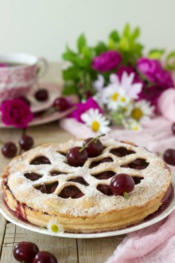 Kirazlı turta kalp şeklinde süsleme çay, bir buket çiçek ve olgun kiraz meyveleri ile bir fincan ile dekore edilmiştir. Vintage tarzı, seçici odak.