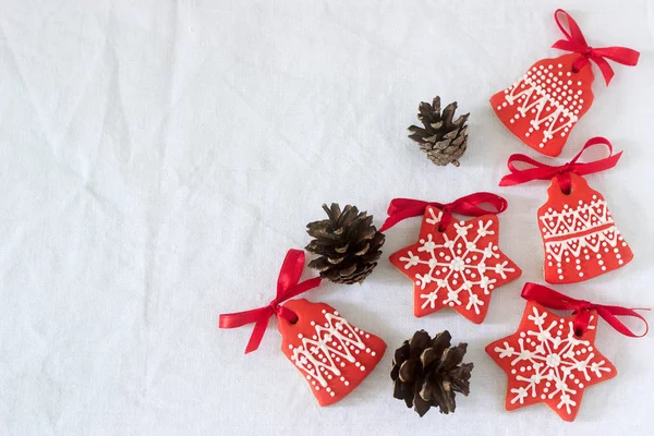 Kerstmis-Nieuwjaar vakantie achtergrond, rode peperkoek cookies en kegels op witte tafel. Kopiëren van ruimte. — Stockfoto