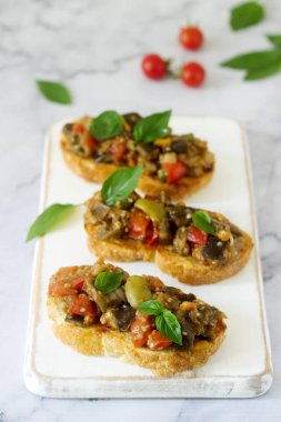 Bruschetta caponata veya ratatouille filmindeki hafif bir arka plan üzerinde çeşitli sebzeler ile. Seçici odak.