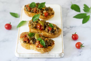 Bruschetta caponata veya ratatouille filmindeki hafif bir arka plan üzerinde çeşitli sebzeler ile. Seçici odak.