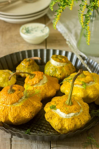 Pattypan squash or pumpkins stuffed with ricotta with basil and dill and served with sour cream sauce. Vegetarian food, rustic style, selective focus.