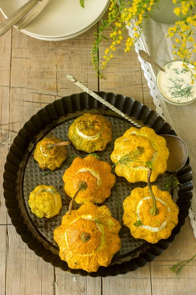 Pattypan squash or pumpkins stuffed with ricotta with basil and dill and served with sour cream sauce. Vegetarian food, rustic style, selective focus.