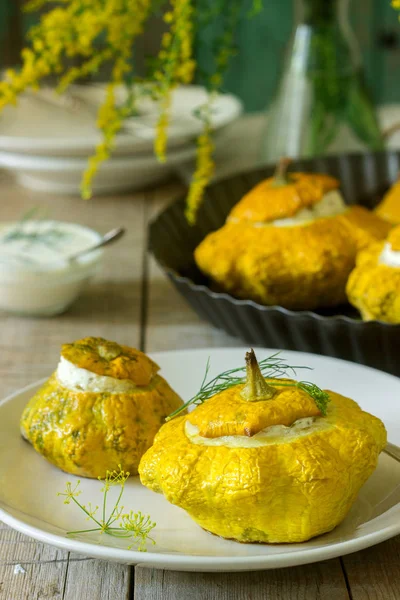 Pattypan squash or pumpkins stuffed with ricotta with basil and dill and served with sour cream sauce. Vegetarian food, rustic style, selective focus.