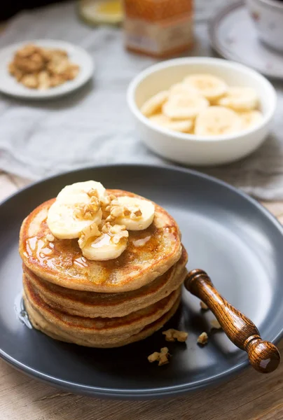 Pancakes with banana, nuts and honey, served with tea. Rustic style.