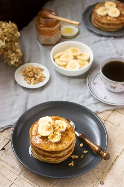Pancakes with banana, nuts and honey, served with tea. Rustic style. — Stock Photo, Image