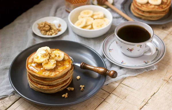 Pancakes with banana, nuts and honey, served with tea. Rustic style. — Stock Photo, Image