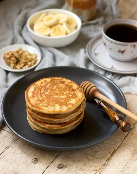 Pancakes with banana, nuts and honey, served with tea. Rustic style. — Stock Photo, Image