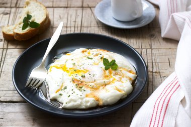 CİLBİR, yoğurt ile baharatlı tereyağı ve otlar, haşlanmış yumurta ekmek ve bir fincan kahve eşliğinde. Seçici odak.