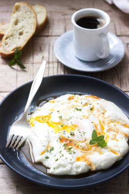 CİLBİR, yoğurt ile baharatlı tereyağı ve otlar, haşlanmış yumurta ekmek ve bir fincan kahve eşliğinde. Seçici odak.